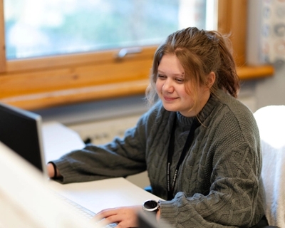 Young female apprentice in front of a computer in office surroundings. Photo