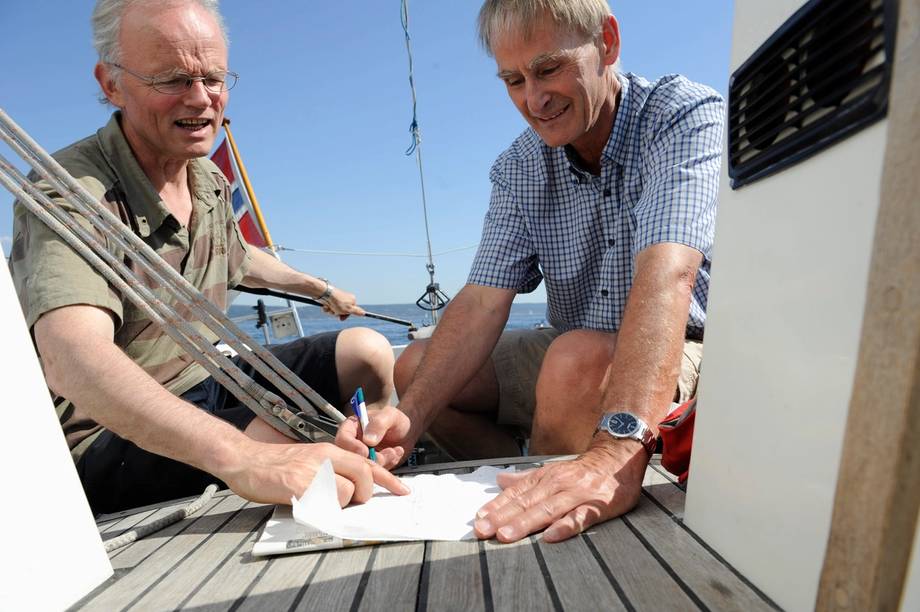 Two men on a boat deck with pen and paper